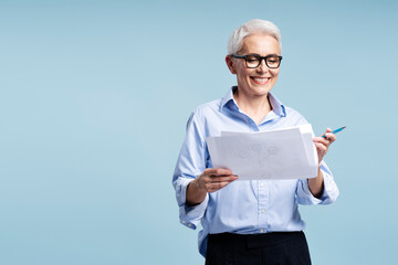 Mature businessman wearing glasses holding business graph isolated on blue background, copy space