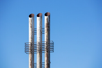 
Three metal chimneys tower into the blue sky