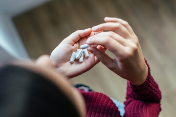 Young woman with depression and anxiety taking pills at home