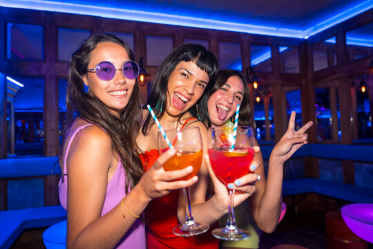 Portrait attractive women in a nightclub dancing with the glasses at a summer night party in a pub