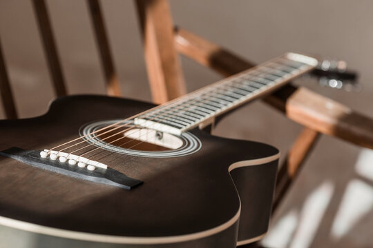 Guitar. Guitar chords. Acoustic guitar. Music. Musical background. An image of an acoustic guitar in a room with a retro armchair. Hard light. Shadows.