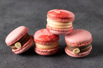 Pink macarons with hazelnuts and caramel on gray background, Closeup
