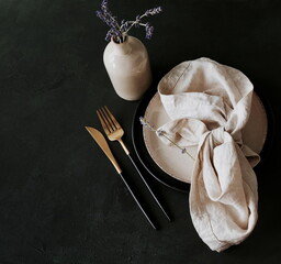 kitchen tableware top view on dark  background Plates,beige linen napkins, cutlery and lavender...
