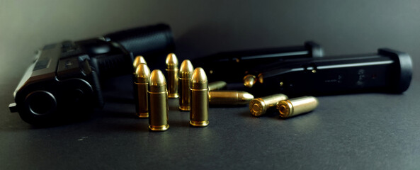 Close-up of pistol and cartridges on dark background, close-up of cartridges