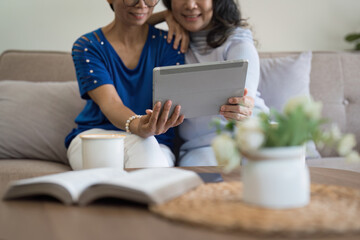 Asian elderly women and friend using social media and living room. Video streaming, happiness and conversation at a house with old people together