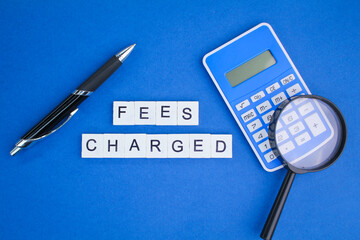 calculator and pen with the word fees charged. payment charged - obrazy, fototapety, plakaty