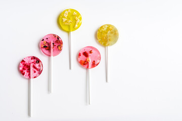yellow and pink homemade lollipops on a white background lie diagonally