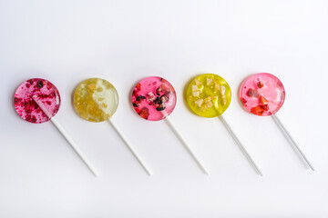 pink and yellow lollipops with pieces of fruit alternating in color laid out in a row