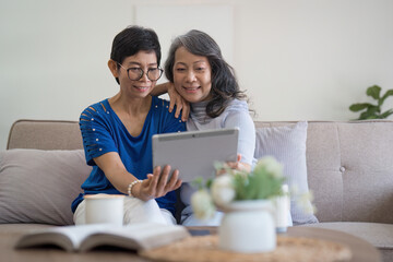 Asian elderly women and friend using social media and living room. Video streaming, happiness and...