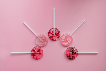 homemade fruit lollipops with pieces of fruit of different shades of pink lie in the shape of a semicircle