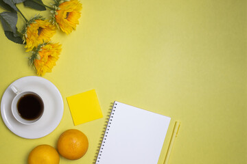 A bright yellow theme with flowers, coffee cup, oranges and notebook.