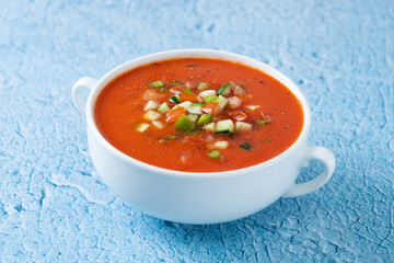 Traditional Spanish gazpacho soup in bowl on blue background