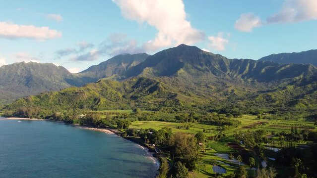 Cinematic Aerial shot of Hanalei Bay and green mountains, beach, boat, ocean with the Hanalei River  near Princeville, Kauai, Hawaii