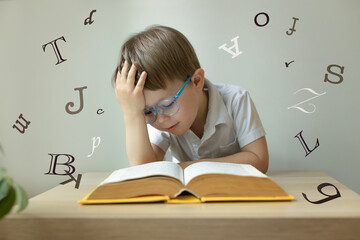 Cute little boy wearing glasses,  open book in front of him, letters around, learn foreign language, dyslexia concept - obrazy, fototapety, plakaty