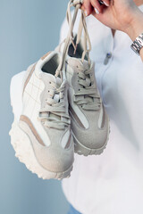 a woman's hand holds a pair of comfortable shoes in her hands. sneakers. woman is ready for walk. High quality photo