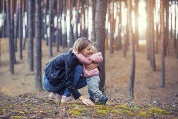 mother and little daughter are walking in a pine forest