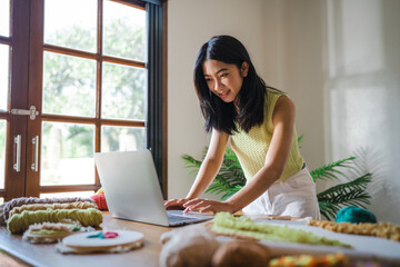 Small business. smiling young entrepreneur Asian Woman. Punch needle craftswoman with laptop computer. in studio workshop. Handmade craft handicraft items