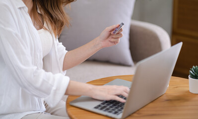 Fototapeta premium Woman shopping&nbsp;on laptop holding credit card for Internet online e-commerce shopping spending money Online shopping Mobile phone laptop technology concept