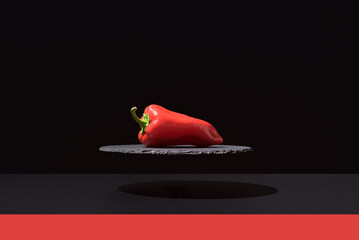 Pimiento piquillo rojo fresco sobre un plato de pizarra y fondo negro