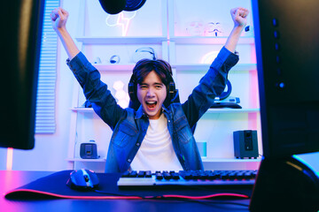 Portrait of Asian male gamer celebrating victory in front of the gaming table. Gamer winning an...