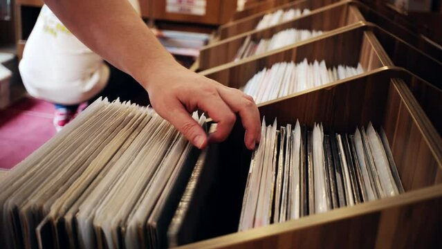 Two men are browsing vintage vinyl records at a store. Looking for rare records.