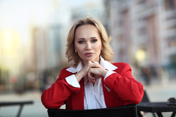 Fototapeta premium blond woman in red pant suit and white blouse closeup photo on urban glass mirror background