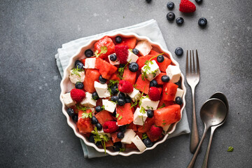 Summer salad with watermelon, feta cheese and blueberry on a gray background. Vegan, European food.