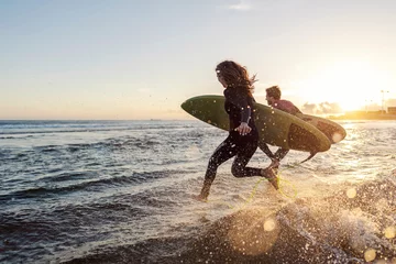 Fototapeten Couple is running into the water with surfboards. © dusanpetkovic1