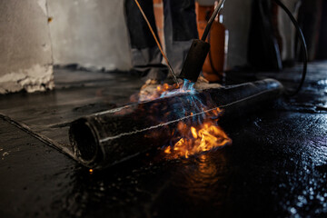 Close up of burning roll melting bitumen roll at construction site.