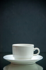Front view of white set of coffee cup and saucer on dark wave background with free space
