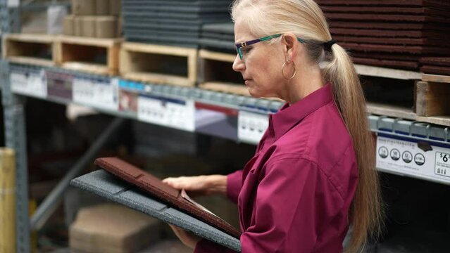 Attractive mature woman shopping looking at architectural rubber paver tiles for deck and garden for home outdoor landscape improvement project.