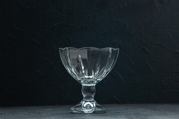 Top view of empty glass jam bowl standing on table on black background with free space