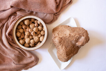 Edible caramel clay stones on a wooden round plate and brown clay stone on a white background flat lay