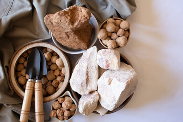 Edible caramel clay stones on a wooden round plate with white and brown clay stones with small garden shovels on a white background