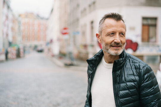 Handsome Older Man Standing At A City Intersection, Looking To The Side