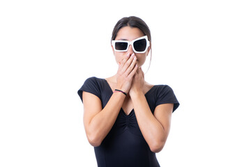 Studio portrait of young brunette model woman wearing funny fancy white sun glasses covering her mouth