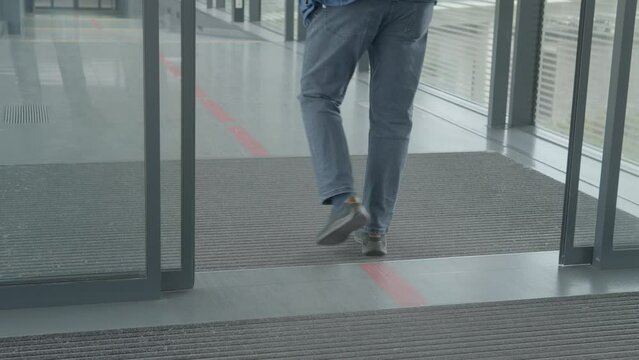 Automatic sliding doors open as walking person triggers sensor, low angle