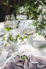 Romantic elegant luxury wedding table decor with white fresh spring blooming cherry apple tree flowers. Glass, candles, floral decoration for special marriage holiday event. No plastic zero waste