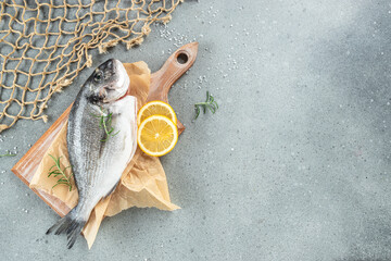 Fresh uncooked dorado or sea bream fish with lemon on a light background. Restaurant menu, dieting,...