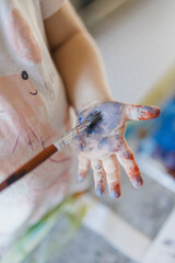 Close up of little girl painting on her own hand with tempera paint,.