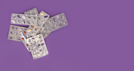 Top view image of used empty blister packs. Group of heap of prescription drug packages.  Half empty half full. Purple background with copy space. Overuse of drugs or addiction concept idea. - obrazy, fototapety, plakaty