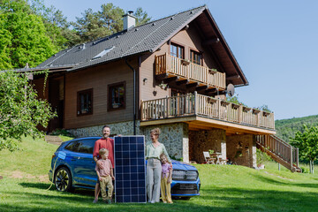 Fototapeta na wymiar Happy family posing with photovoltaics panel during their electric car charging.