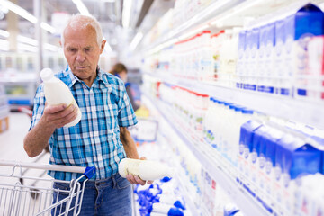 old age man choosing milk in supermarket