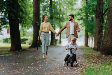 Obraz premium Young family with little son on walk in city park after work.