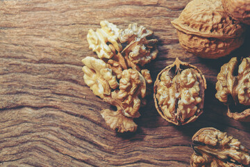 Raw brown organic walnut kernels with shell on rustic wooden table. Selected focus