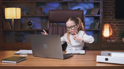 Dynamic little office worker taking short break and dancing happily with hands in fancy office. Active child with ponytails relaxing and making small entertainment. Concept of leisure activity.