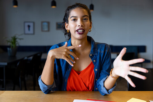 Biracial casual businesswoman talking and gesturing during video call at desk