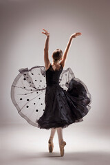 Ballerina in Ballet Studio with Ballet Shoes or Pointe and Black Dress. Back to Camera. Back light © Maryana