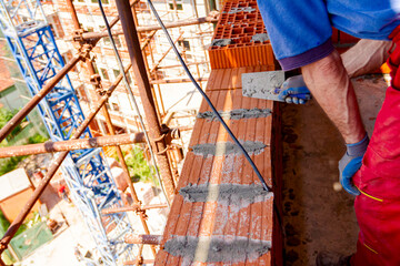 Builder using spatula to remove surplus mortar