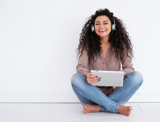 afro american young woman sitting on floor with tablet pc computer and headphones listening to...